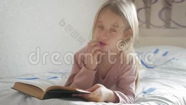 女孩躺在床上看书。 女孩孩子长发可爱睡衣<strong>放松</strong>和阅读童话书。 <strong>惬意</strong>的时光